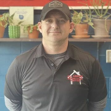 Professional contractor in branded polo shirt and cap standing in workshop
