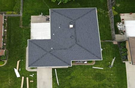 Aerial view of modern house with dark gray roof surrounded by green lawn