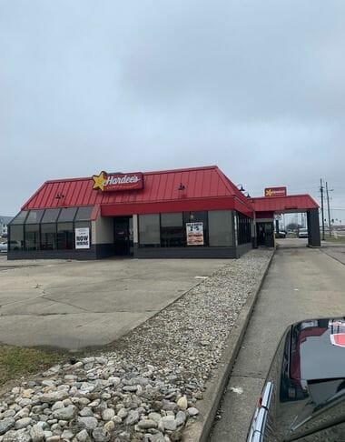 Hardee's fast food restaurant with red roof and stone exterior on overcast day