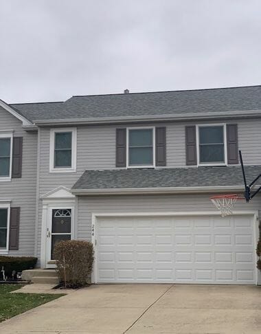 Modern gray vinyl siding townhouse with white garage door and green shutters