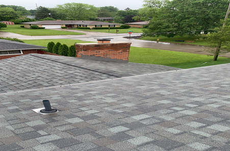 Gray shingle roof view overlooking residential neighborhood with brick chimney