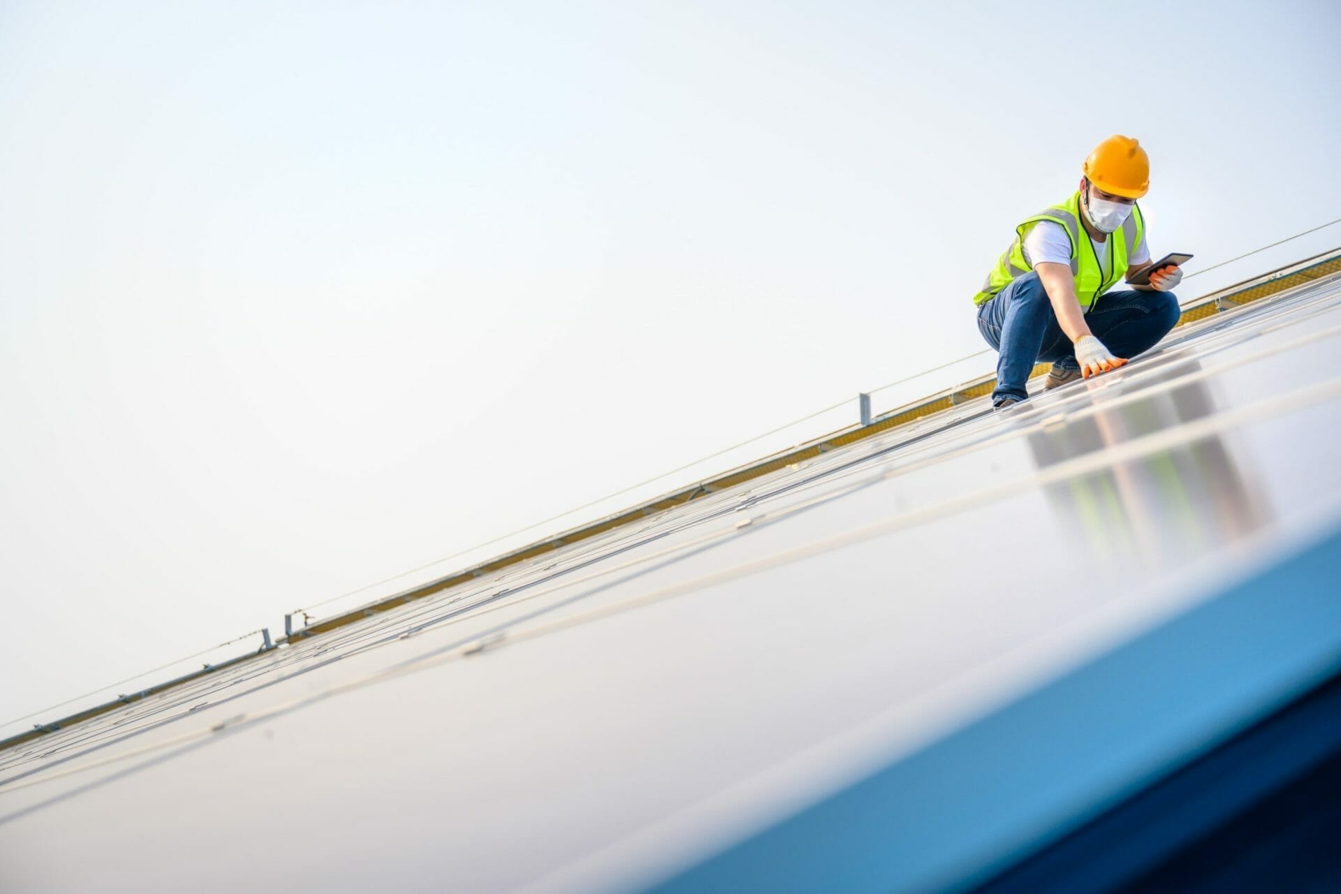 Solar panel technician in safety gear inspecting rooftop solar installation