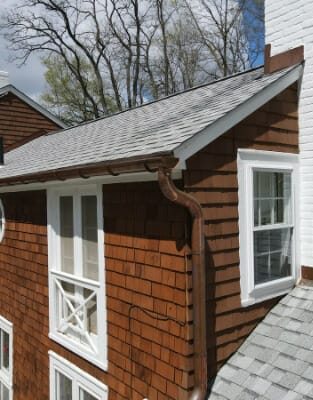 Cedar shake siding home with white trim windows and gray shingle roof