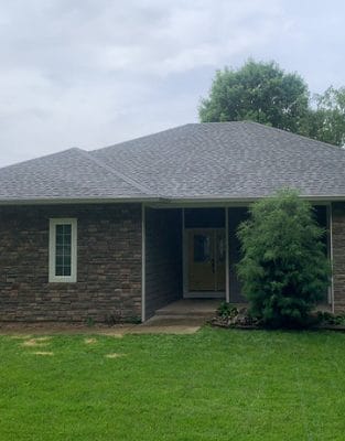 Single-story brick ranch home with gray shingle roof and green lawn