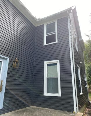 Dark gray vinyl siding on modern two-story house with white trim windows