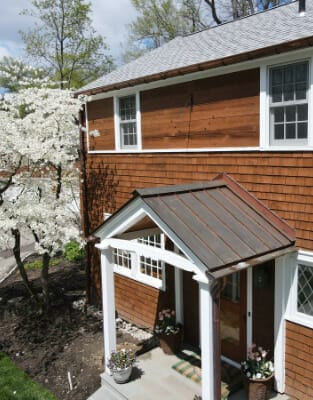Cedar shake house with metal roof and white trim featuring covered entrance