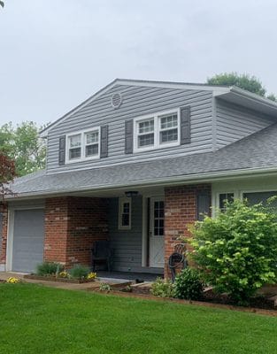 Two-story brick and vinyl siding house with white trim windows and green lawn