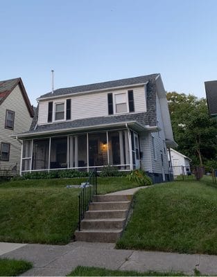 Two-story white colonial house with black shutters and front porch steps