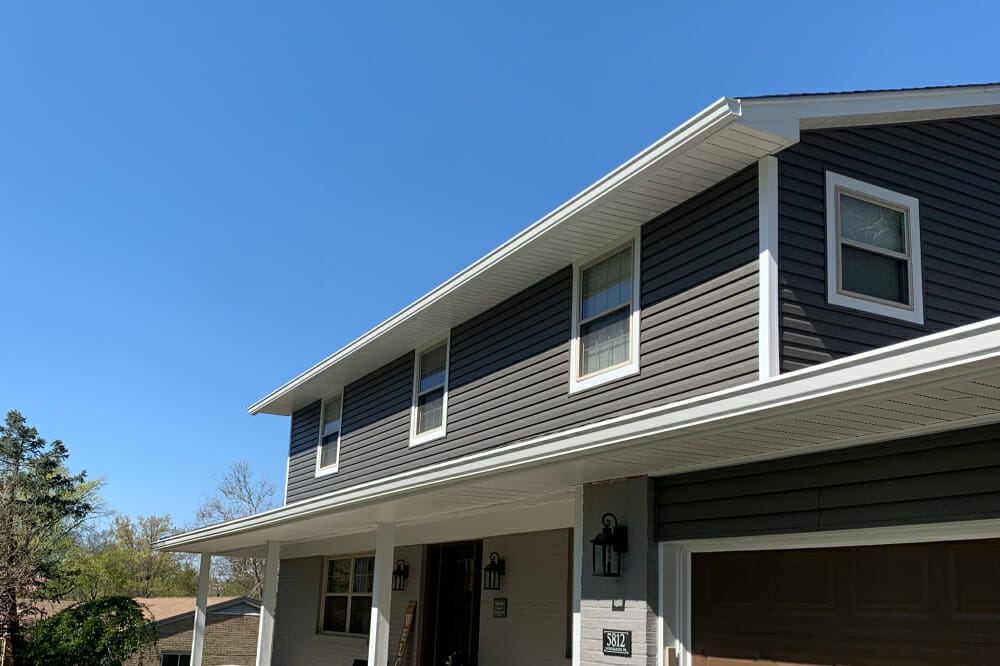 Modern two-story house with gray siding and white trim under clear blue sky