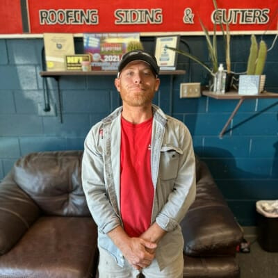 Professional contractor in work clothes sitting in office with roofing business sign