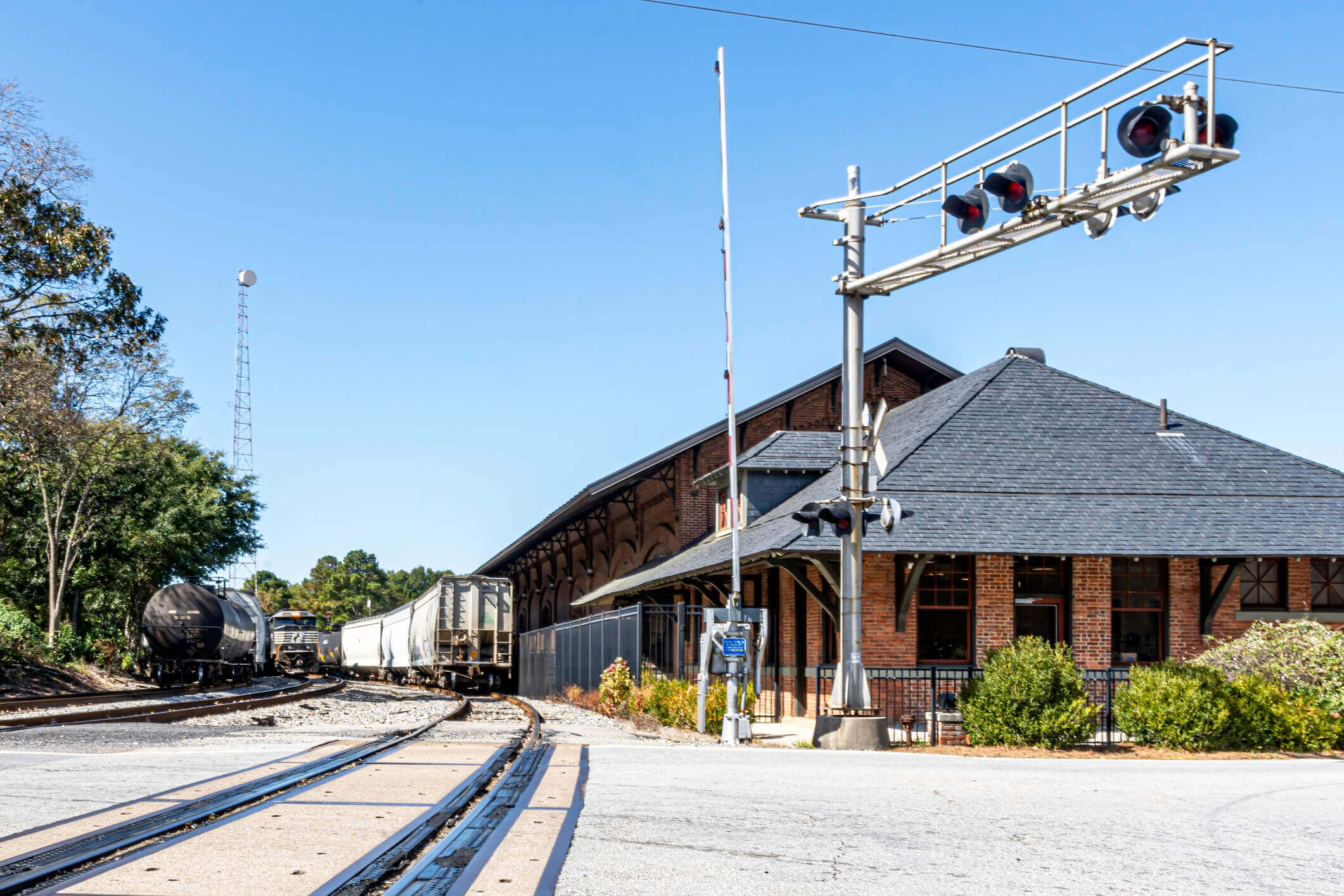 Historic brick train station with railroad tracks and signal lights on sunny day