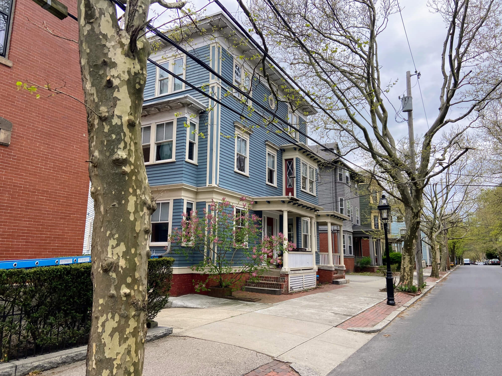 Blue Victorian house with white trim on tree-lined residential street