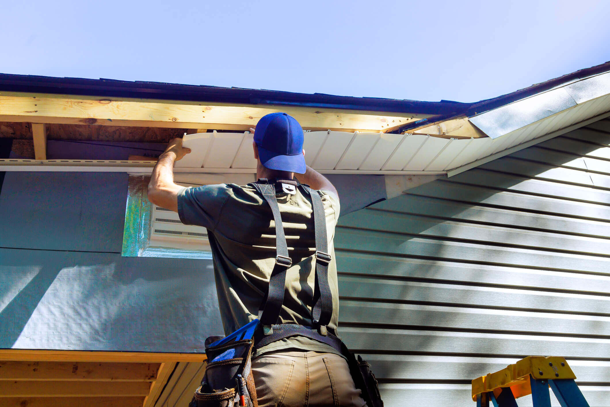 Construction worker installing roof panels on residential home exterior project